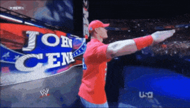 a man in a red shirt is standing in front of a sign that says john cena