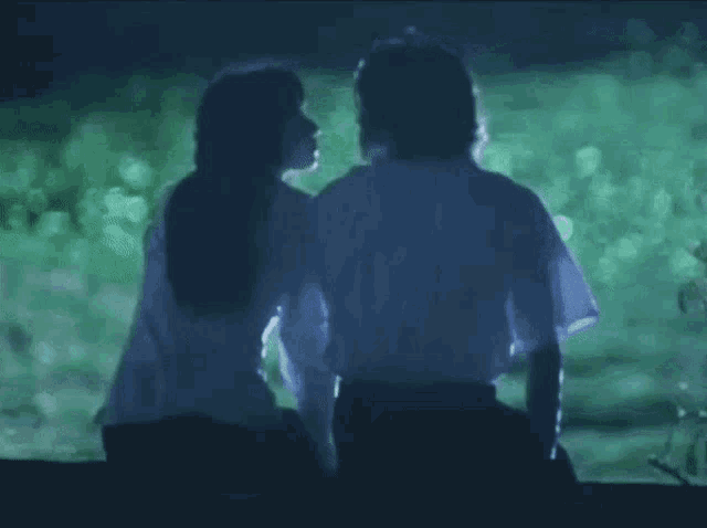 a man and a woman are sitting next to each other in front of a green background