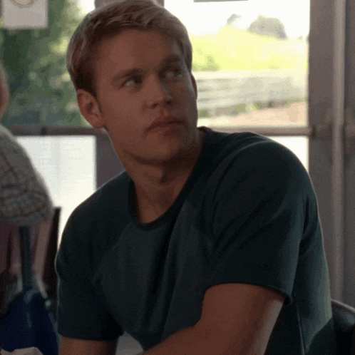 a man in a green shirt is sitting in a chair