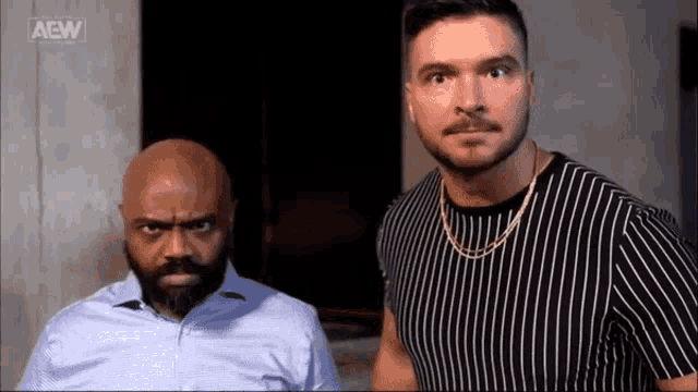 two men are standing next to each other looking at the camera .