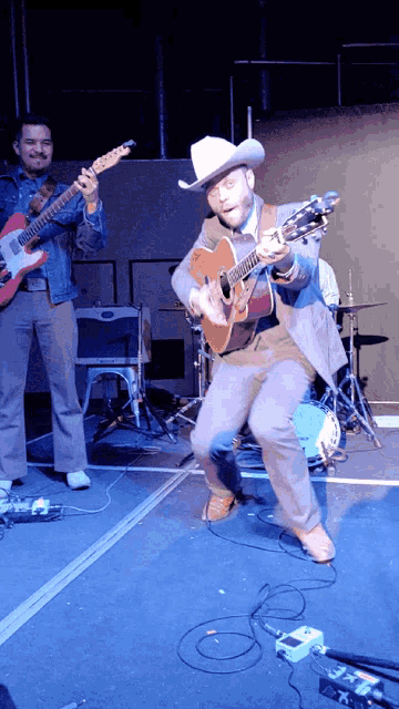 a man in a cowboy hat playing a guitar on stage
