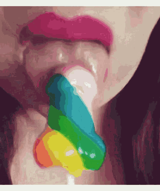 a close up of a woman licking a rainbow lollipop