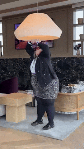 a woman in a leopard print skirt is holding a large lamp over her head