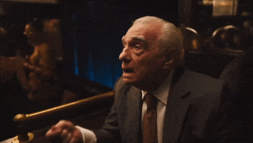 an older man in a suit and tie sits at a table