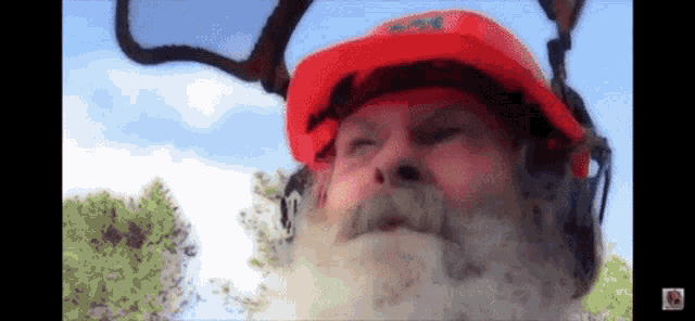 a man with a beard wearing a red helmet with a sticker that says ' no smoking '