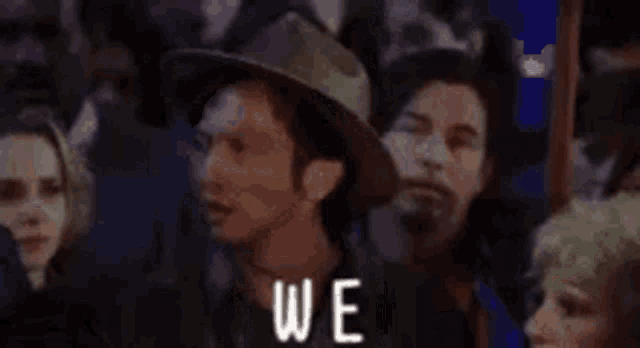 a group of people are standing in a crowd with the words `` again '' written on the bottom .