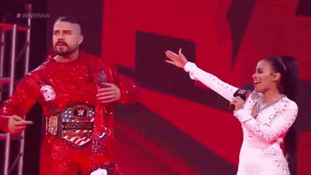 a man and a woman are standing next to each other on a stage . the woman is holding a microphone .
