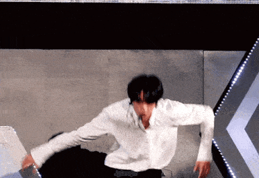 a man in a white shirt is dancing on a stage in front of a crowd .