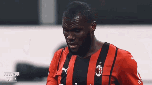 a soccer player wearing a red and black jersey with the ac milan logo