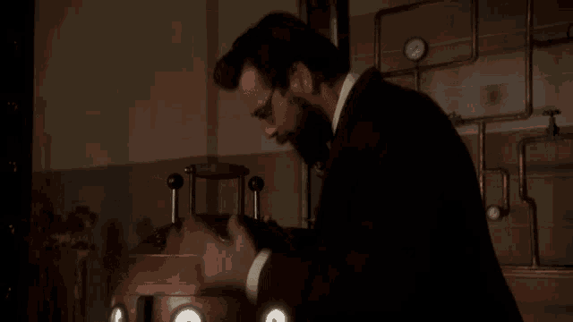 a man with a beard is working on a machine in a dark room