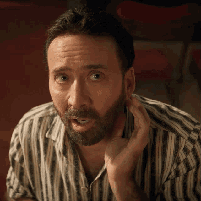 a man with a beard wearing a striped shirt is making a surprised face
