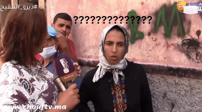 a woman wearing a scarf and a mask is being interviewed by a reporter