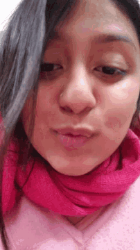 a young woman wearing a pink scarf around her neck