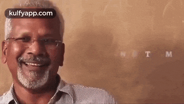 a man with glasses and a beard is smiling and looking at the camera .