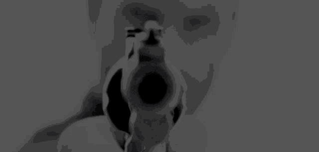 a black and white photo of a man pointing a gun at the camera