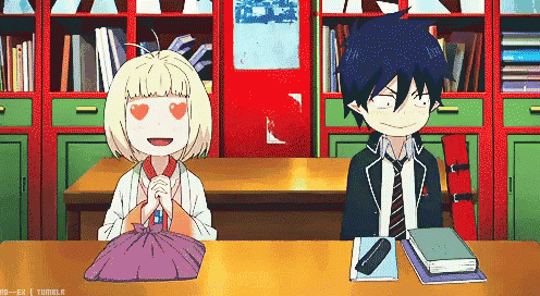a boy and a girl are sitting at a table in front of a bookshelf