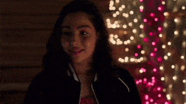 a woman is standing in front of a wall with christmas lights .