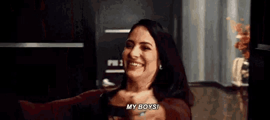 a woman is laughing and saying `` my boys '' while sitting in a dark room .