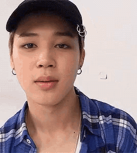 a close up of a person wearing a plaid shirt and a baseball cap .