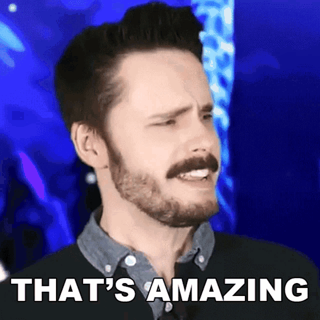 a man with a beard and mustache says that 's amazing in front of a blue background