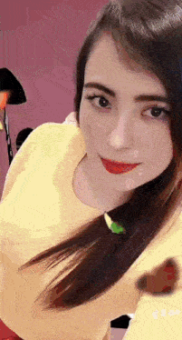 a woman in a yellow shirt is taking a selfie