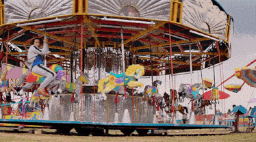 a man is riding a merry go round at a carnival