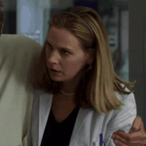 a woman in a lab coat is talking to a man in a suit