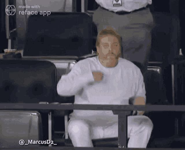 a man in a white shirt is sitting in the stands at a baseball game .