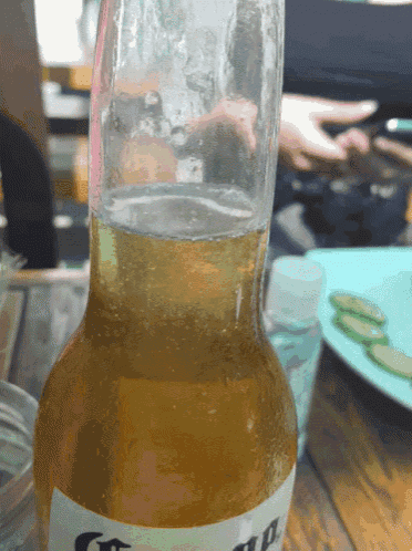 a bottle of corona beer is sitting on a wooden table