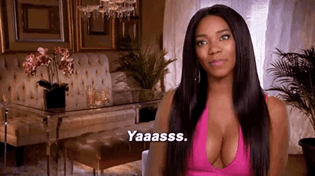 a woman in a pink tank top is sitting in a living room with a couch .