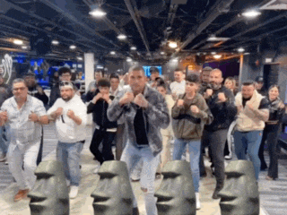 a group of people are dancing in a room with statues of moai heads