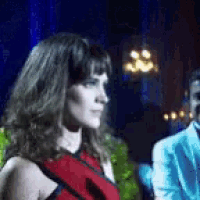 a woman in a red dress is standing in front of a man in a blue suit