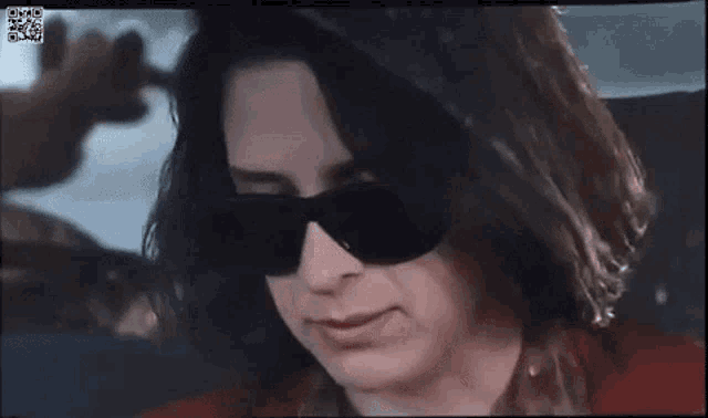 a close up of a woman wearing sunglasses and a red shirt