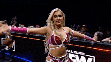 a woman in a red and pink outfit is dancing in front of a crowd