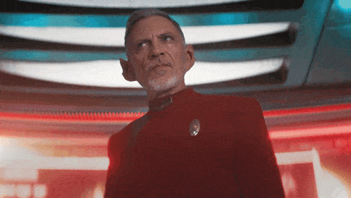 a man in a red suit with a star trek pin on his jacket