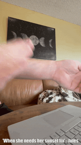a man 's hand is reaching out in front of a laptop with the caption " when she needs her sunset fix jules "