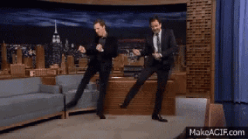 two men in suits and ties are dancing in front of a makeagif.com screen