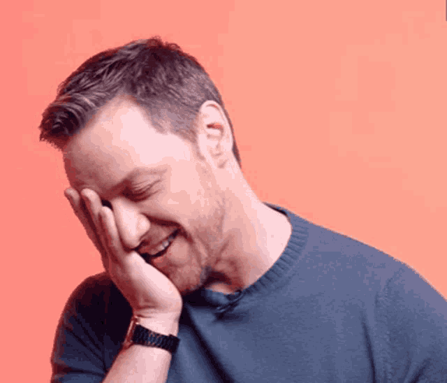 a man covering his face with his hand while smiling