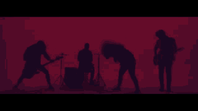 a group of people playing instruments in a dark room with a red background