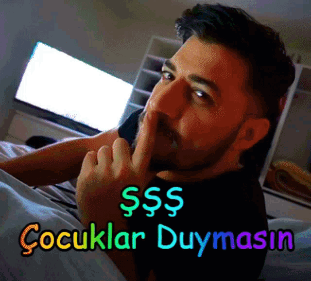 a man laying on a bed with his finger on his lips and the words " cocuklar duymasin " written below him