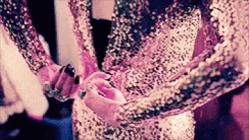 a woman in a sequined dress is holding a pink object .
