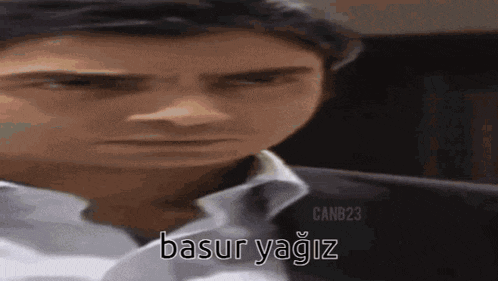 a man in a suit and tie is making a funny face and says basur yagiz