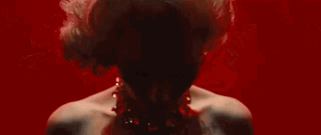 a woman in a red dress is surrounded by lots of hands .