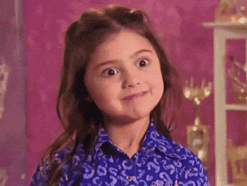 a little girl is making a funny face while wearing a blue shirt with a leopard print .
