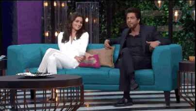 a man in a suit sits next to a woman sitting on a blue couch