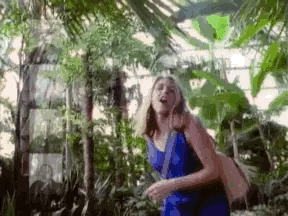 a woman in a blue dress is walking through a greenhouse .