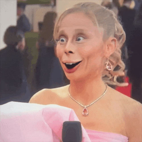 a woman wearing a pink dress and a diamond necklace looks surprised
