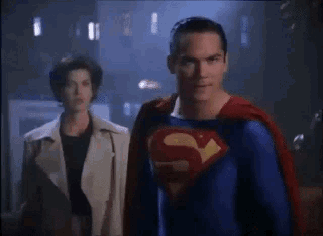 a man in a superman costume is standing next to a woman in a trench coat