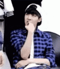 a young man wearing a blue plaid shirt and a white hat is sitting on a couch .
