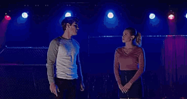 a man and a woman are standing next to each other on a stage in front of a blue light .